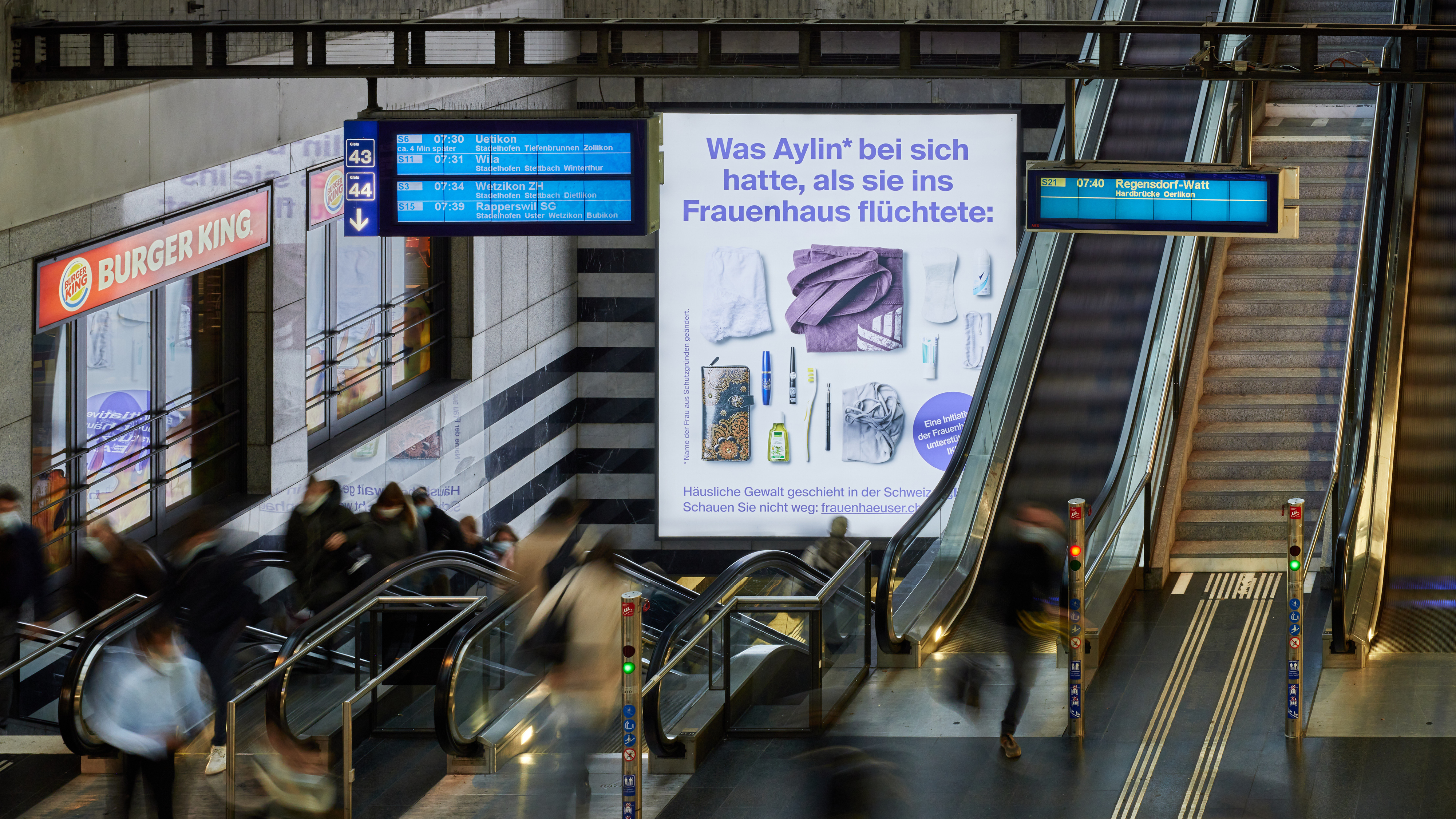 A picture of a busy escalator with a DAO ad behind it
